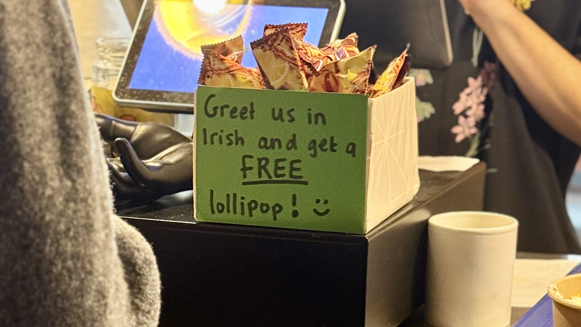Low-fi prototype: a small sign inviting customers to say a phrase in Irish in exchange for a lollipop.
